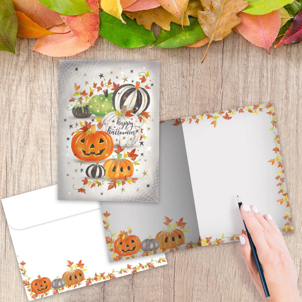 Halloween-themed card with pumpkins and leaves on a wooden surface with fall leaves.