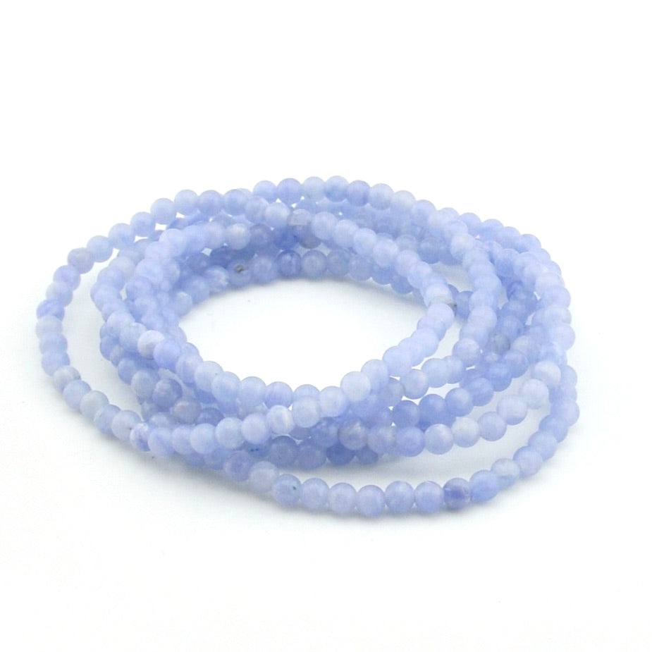 Multiple light blue beaded bracelets stacked on a white background