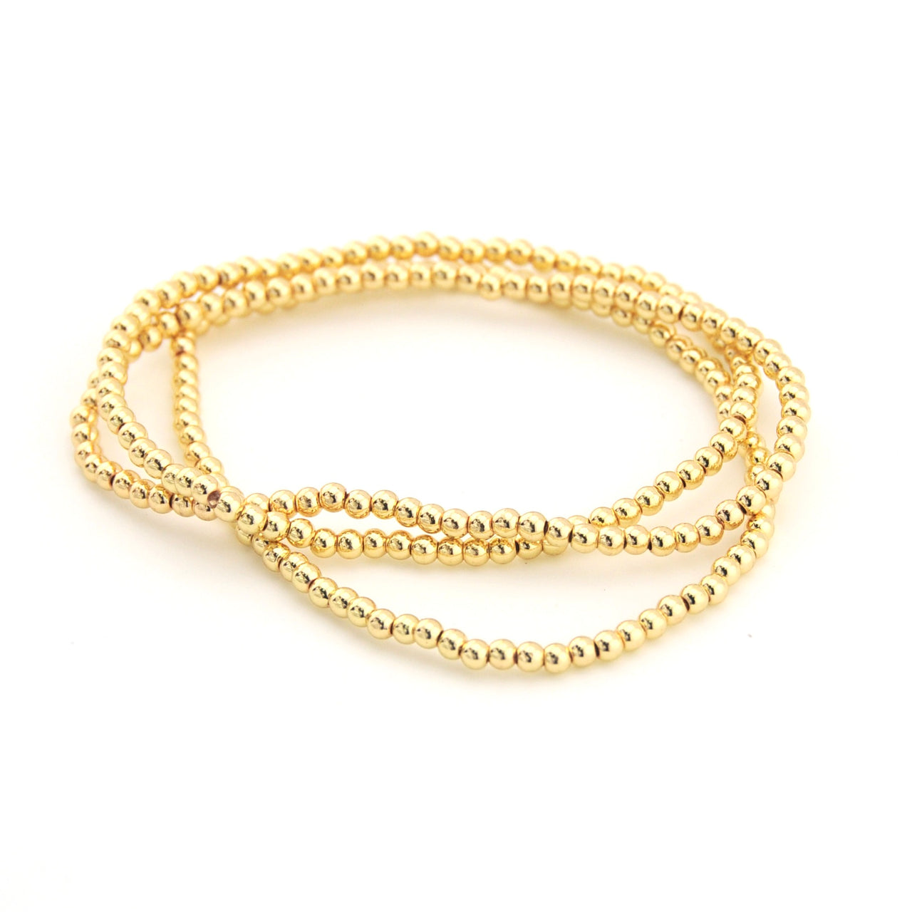 Three gold beaded bracelets stacked on a white background