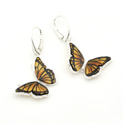 A pair of butterfly drop earrings with orange and black patterned wings set in silver, suspended from silver leverback hooks on a white background.