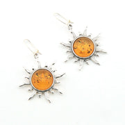 Sun-shaped earrings with amber stones on a white background