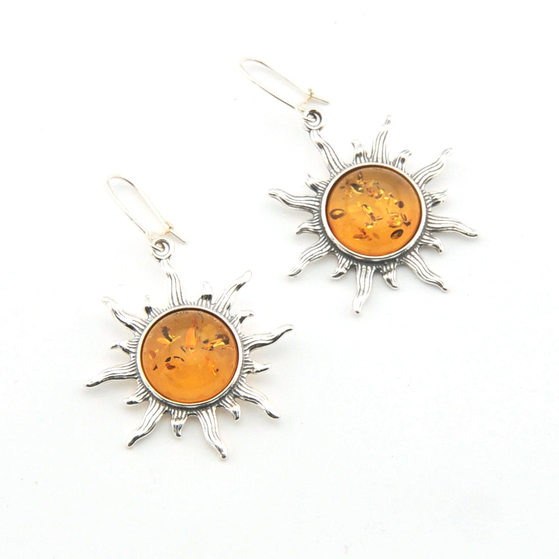 Sun-shaped earrings with amber stones on a white background