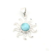 Silver sun-shaped pendant with a blue gemstone on a white background