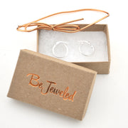 Jewelry box with 'Be Jeweled' branding containing hoop earrings and a headband.