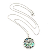 A silver dragonfly pendant necklace featuring a detailed silver dragonfly over an iridescent green and blue abalone shell background, displayed on a clean white background.