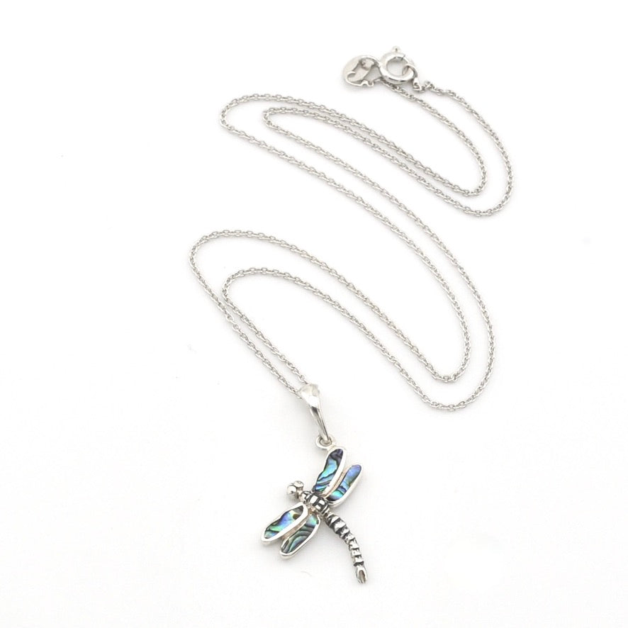 A silver dragonfly pendant necklace with iridescent blue-green inlay on the wings, displayed on a clean white background.