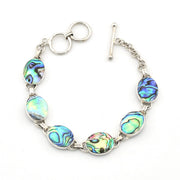 A silver-toned bracelet featuring five oval abalone shell beads with iridescent blue, green, and gold patterns, shown on a plain white background.