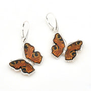 A pair of silver leverback earrings featuring butterfly wings with orange, brown, and black patterned inlay, displayed on a clean white background.