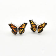A pair of butterfly-shaped stud earrings with orange and black patterned wings and silver-toned metal borders, shown on a plain white background.