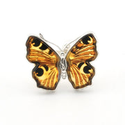 A butterfly-shaped ring featuring amber-brown wings with black eye-like spots and a silver-toned metal setting, shown on a plain white background.