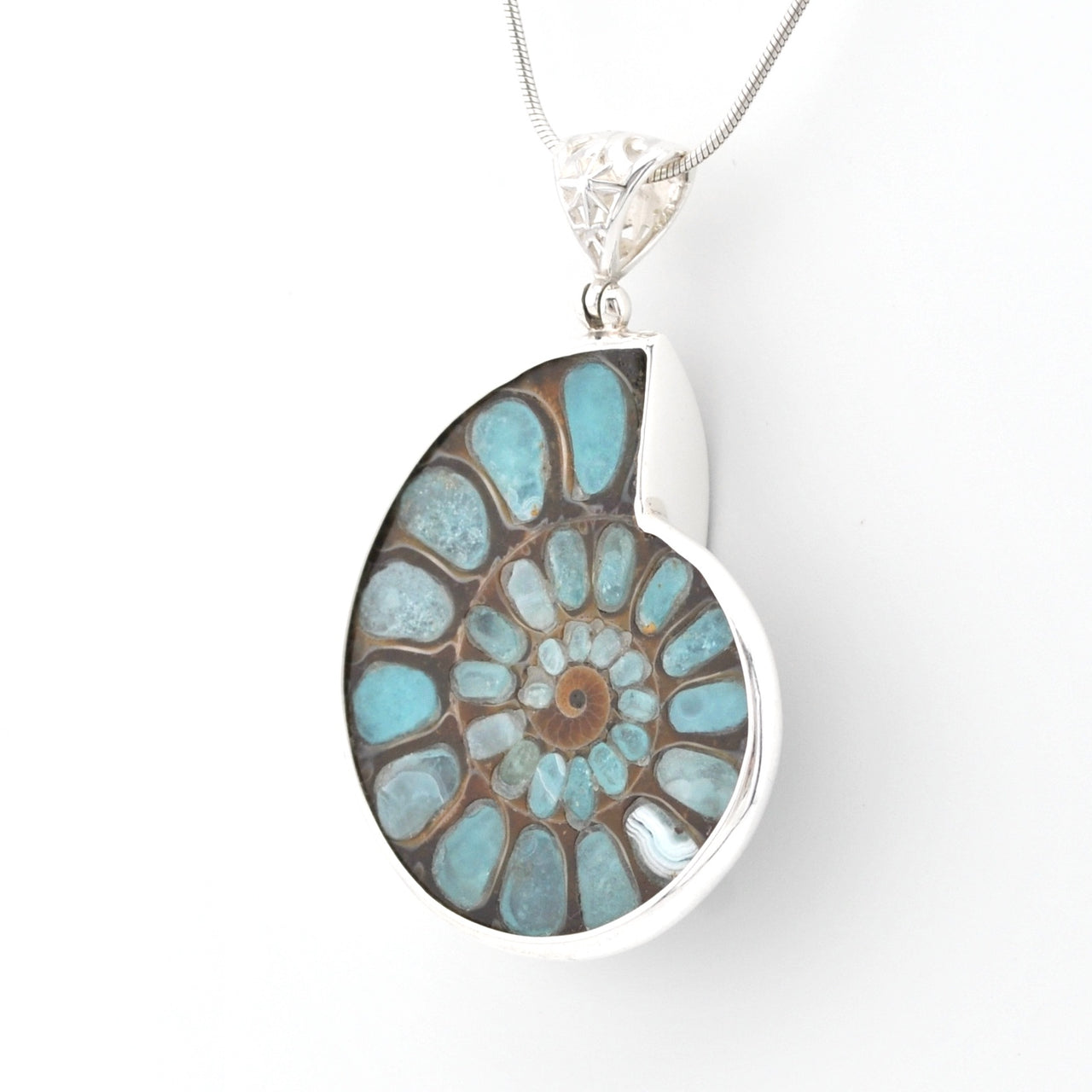 A silver pendant necklace featuring a polished ammolite shell-shaped stone with a spiral pattern of light blue, turquoise, and brown, suspended from a silver chain on a white background.