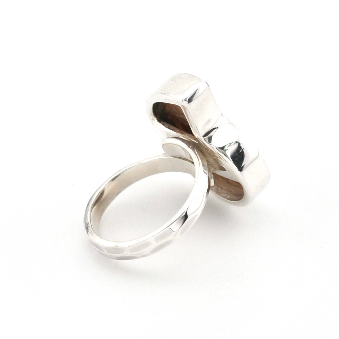 A polished silver ring with a geometric, block-like top and a smooth band, shown on a plain white background.