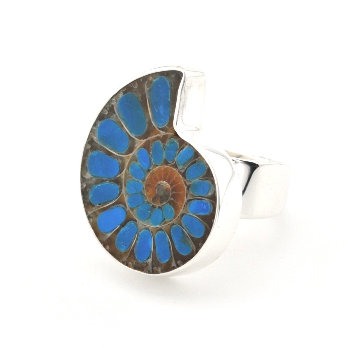 A silver ring featuring a large, circular inlay of an ammonite fossil showing vibrant blue, brown, and tan layers, set against a plain white background.