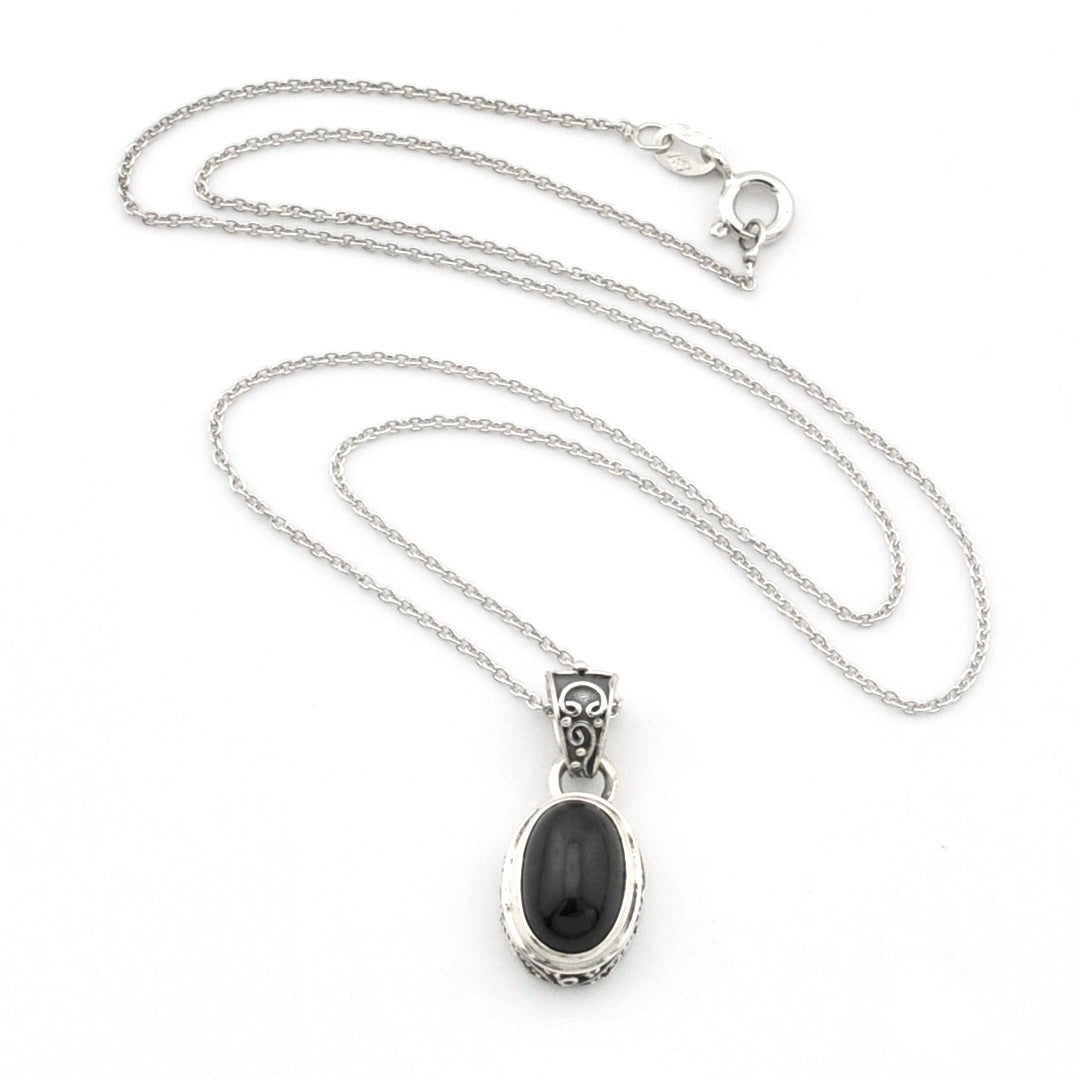 A sterling silver chain necklace with an oval pendant featuring a black cabochon stone in a silver bezel setting, displayed on a clean white background.