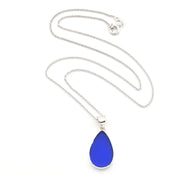 A silver necklace with a teardrop-shaped cobalt blue glass pendant, displayed on a clean white background.