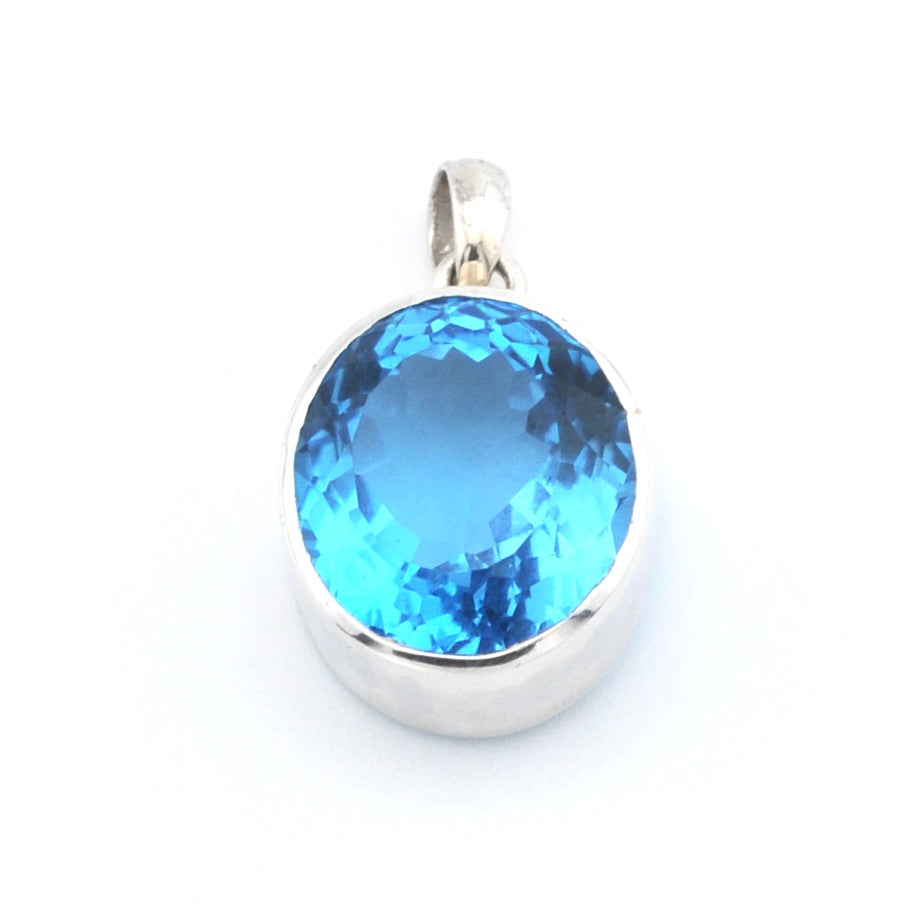A round-cut light blue gemstone pendant set in a polished silver bezel with a bail, shown on a plain white background.