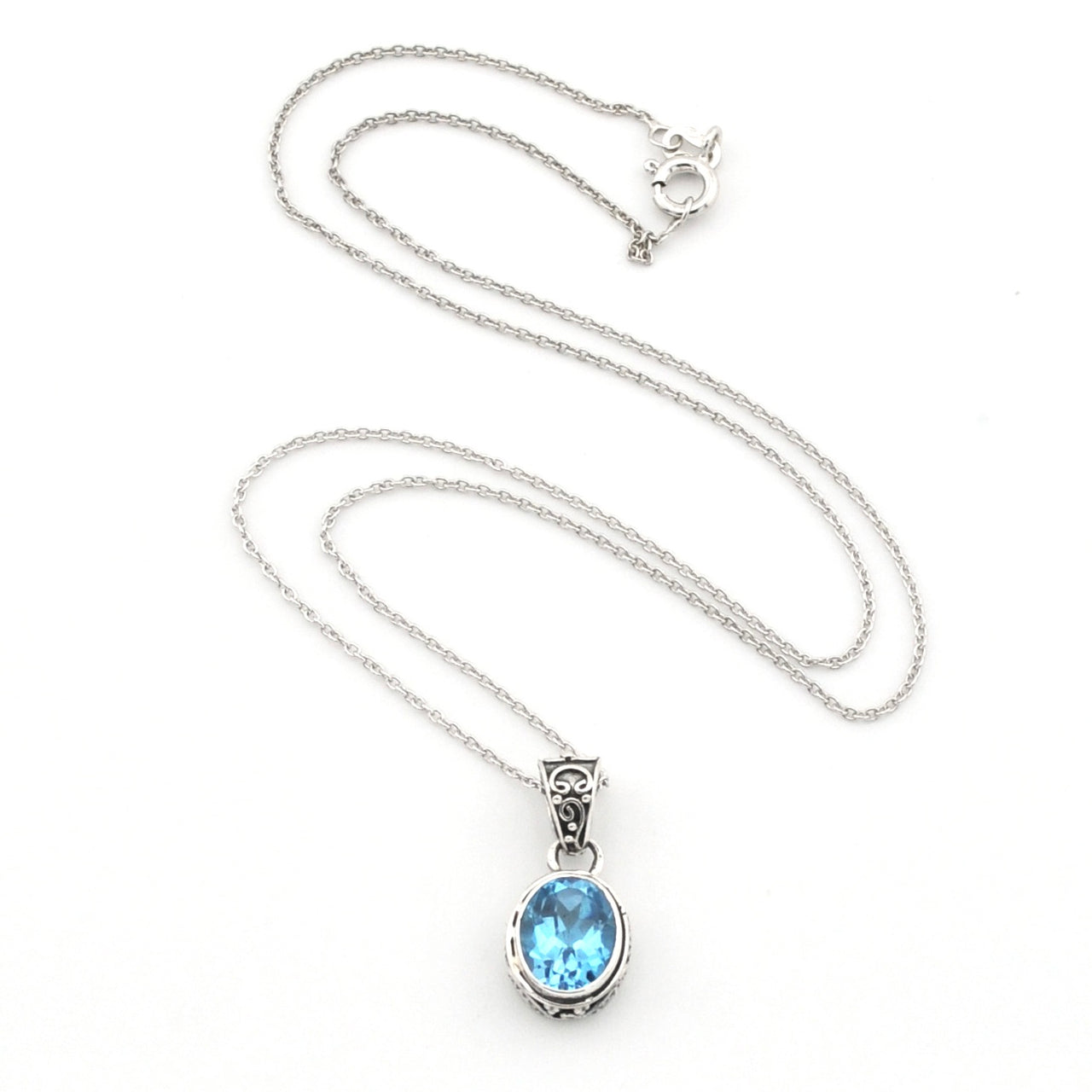 A silver chain necklace with an oval bezel setting holding a light blue gemstone, displayed on a clean white background.