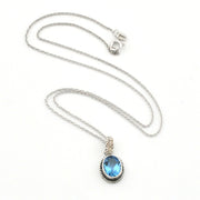 A silver chain necklace with an oval pendant featuring a light blue gemstone in a silver bezel setting, displayed on a clean white background.