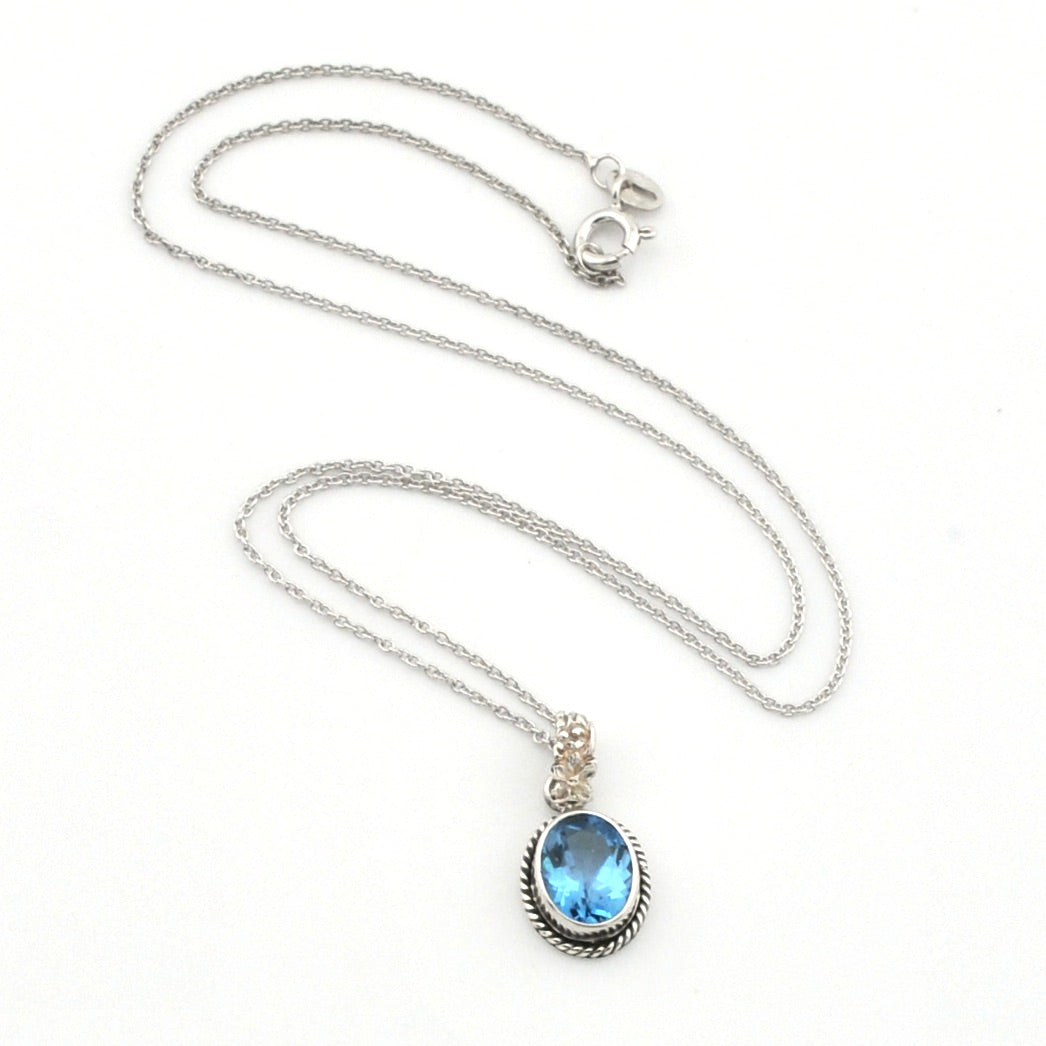 A silver chain necklace with an oval pendant featuring a light blue gemstone in a silver bezel setting, displayed on a clean white background.