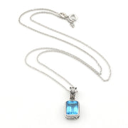 A silver-toned necklace featuring a rectangular light blue gemstone pendant with a decorative silver bail, displayed on a clean white background.
