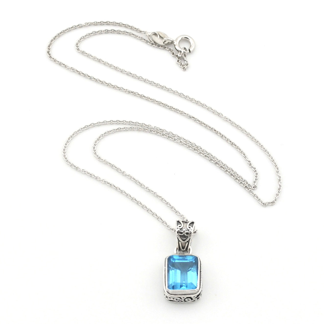 A silver-toned necklace featuring a rectangular light blue gemstone pendant with a decorative silver bail, displayed on a clean white background.