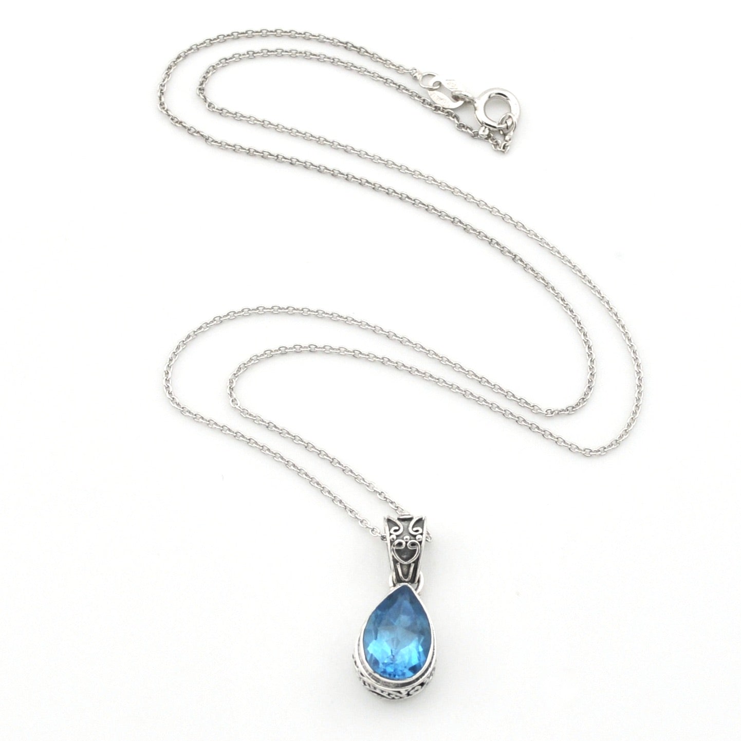 A silver chain necklace with a teardrop-shaped blue gemstone pendant in a silver setting, displayed on a clean white background.