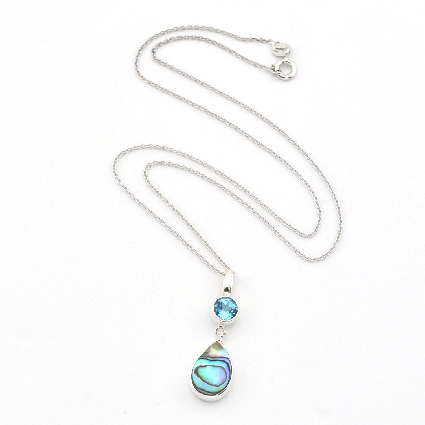A silver necklace featuring a teardrop-shaped abalone shell pendant and a small round blue gemstone, displayed on a clean white background.