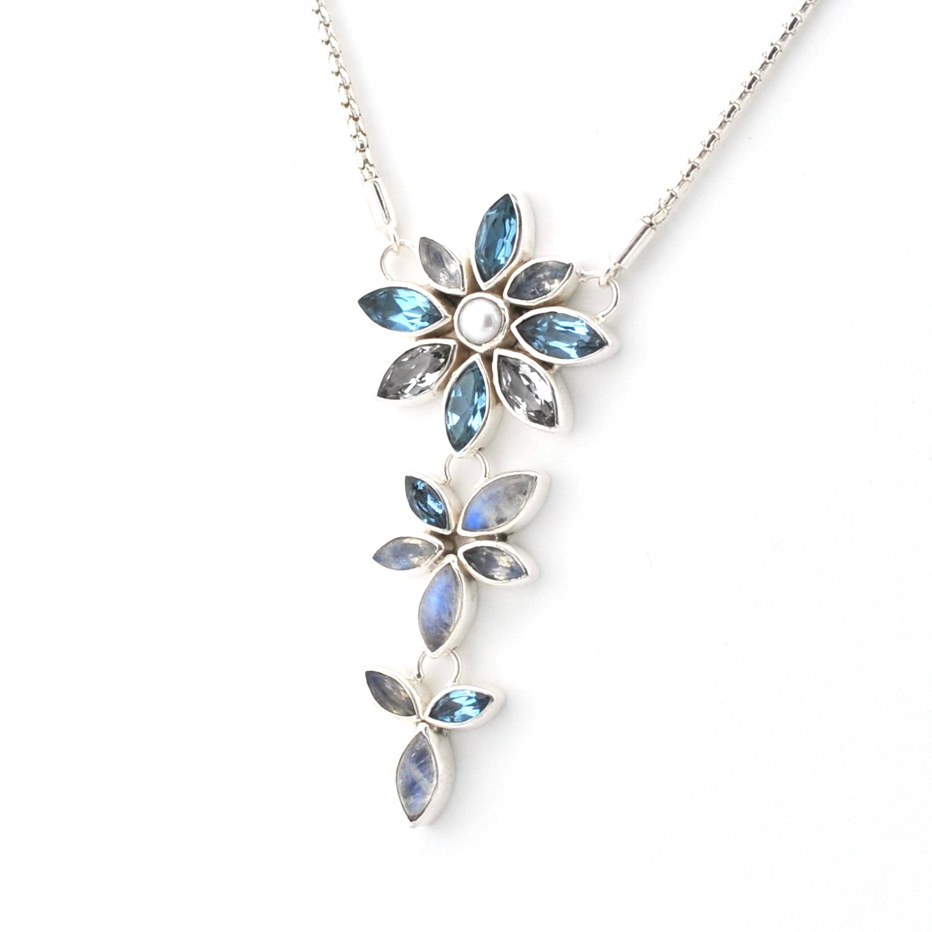 A silver-toned dangle necklace featuring three vertical rows of flower-shaped settings with marquise-cut blue iridescent stones and a small round pearl in the center of the top flower, shown on a white background.