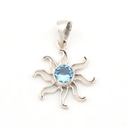 Silver sun-shaped pendant with a blue gemstone on a white background