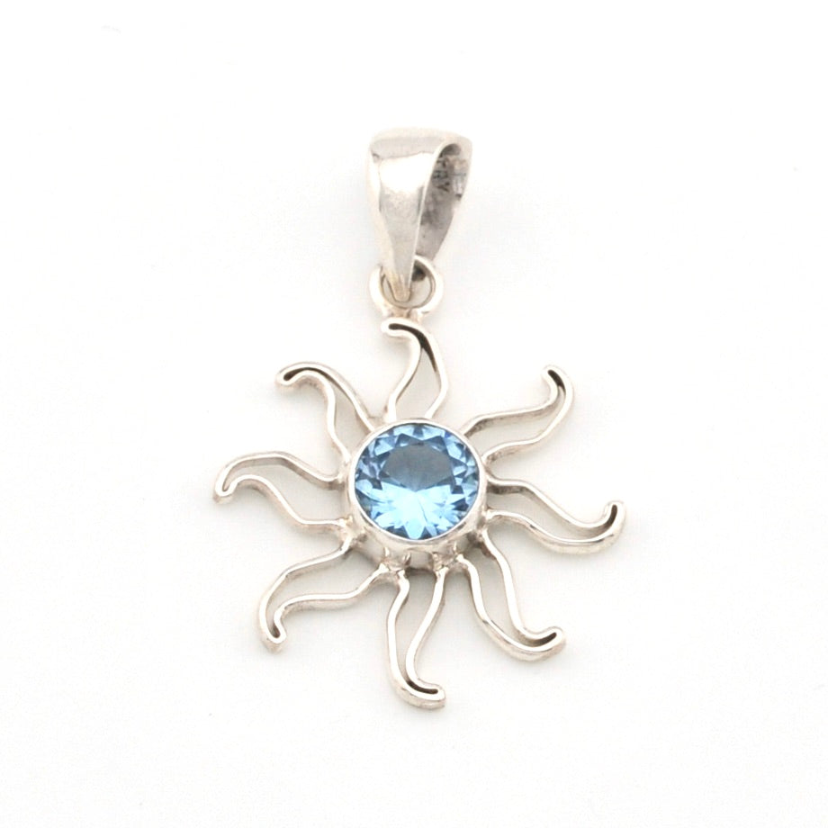 Silver sun-shaped pendant with a blue gemstone on a white background