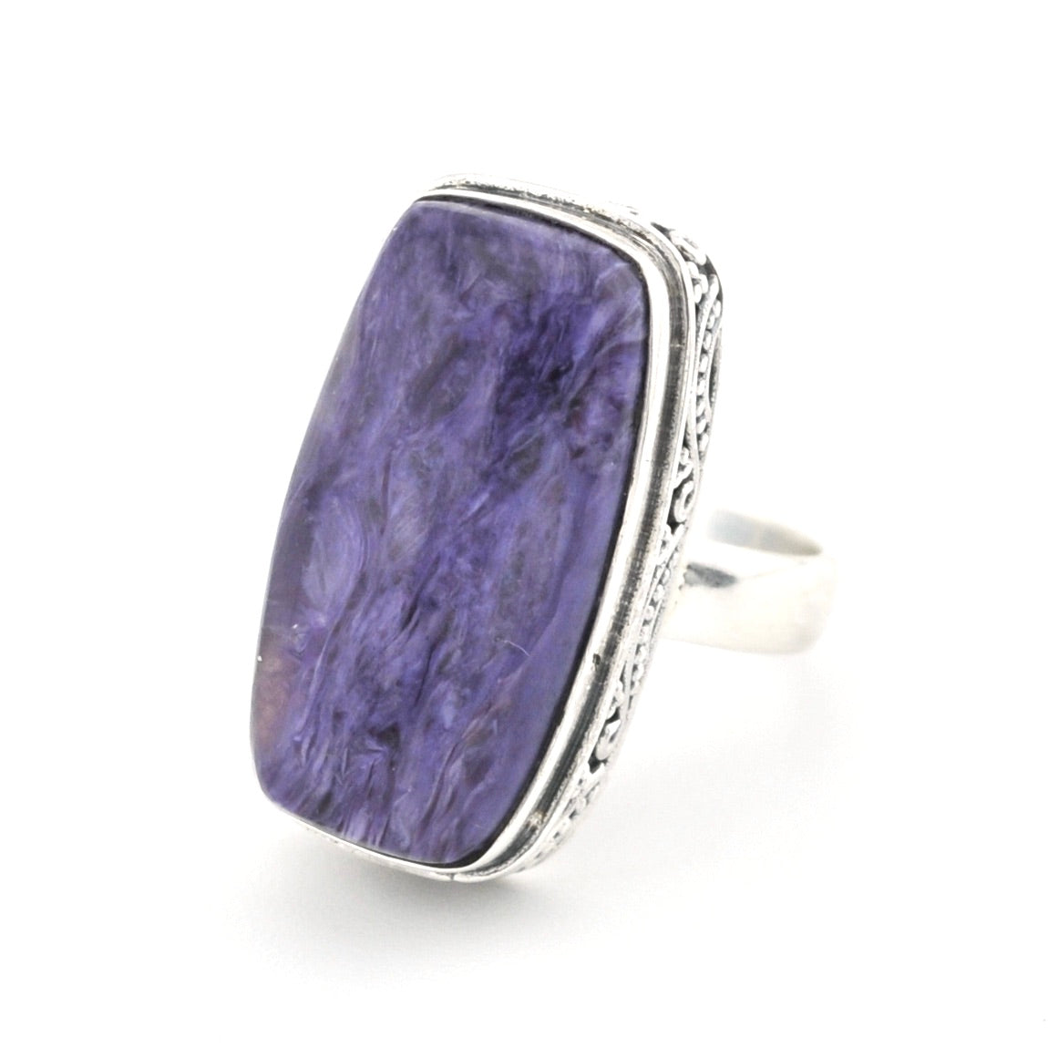 A silver ring featuring a large, rectangular purple stone with natural marbled patterns, set in an ornate silver bezel on a white background.