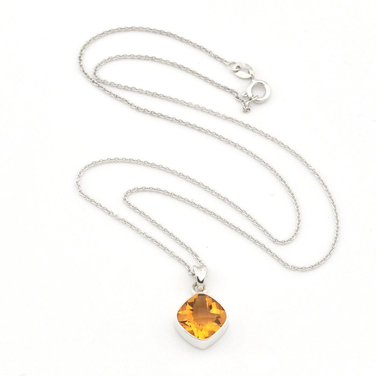 A silver chain necklace with a cushion-cut yellow amber pendant in a silver bezel setting, displayed on a clean white background.