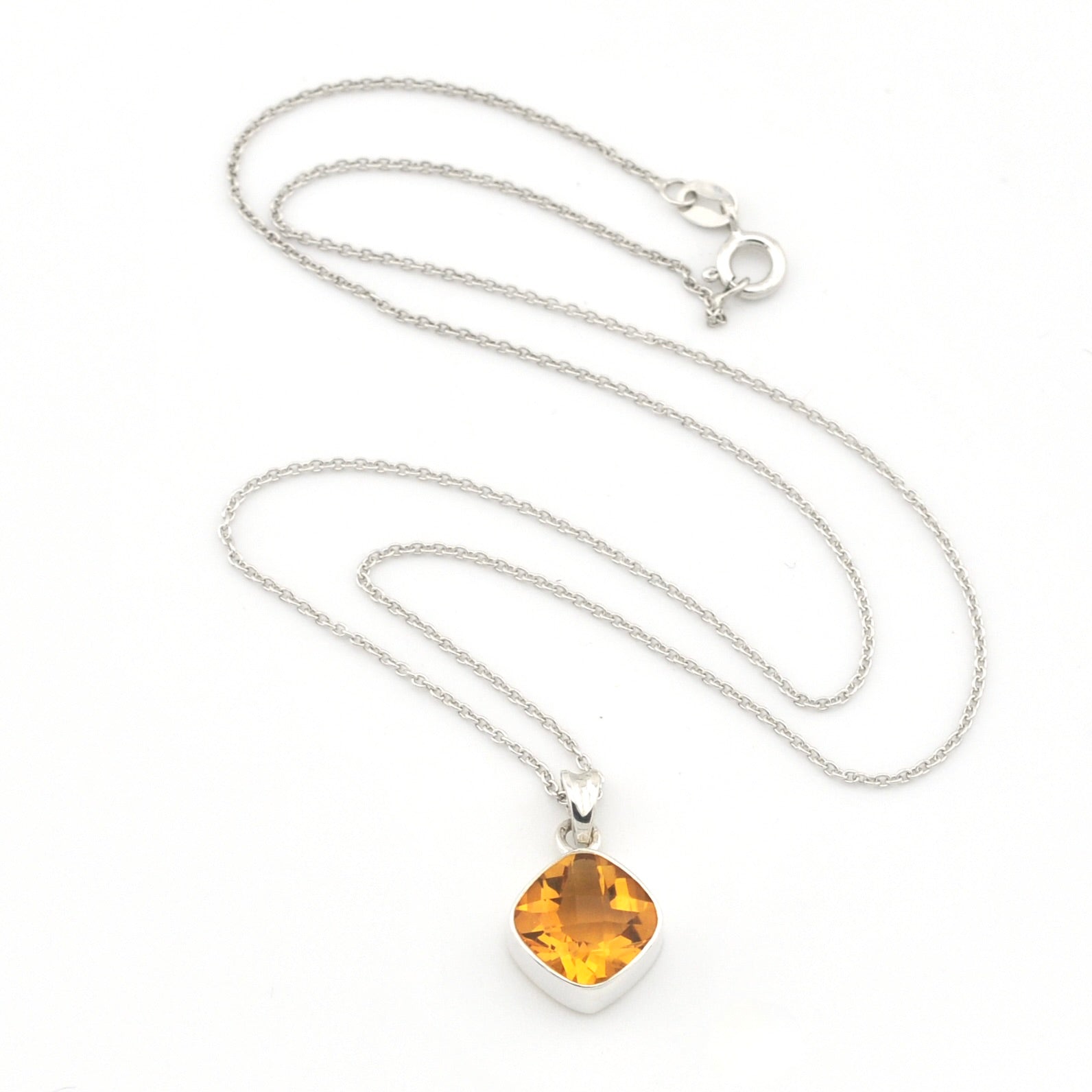 A silver chain necklace with a cushion-cut yellow amber pendant in a silver bezel setting, displayed on a clean white background.