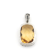 A silver pendant featuring a large, faceted citrine gemstone in a rounded rectangular bezel setting, shown against a plain white background.