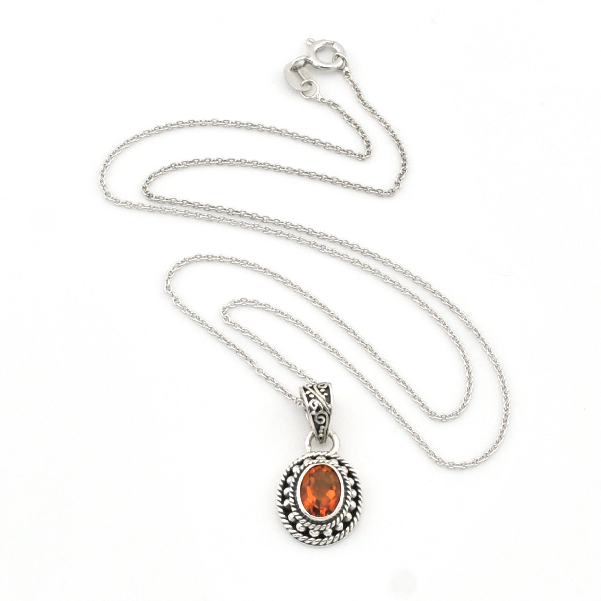 A silver chain necklace with an oval pendant featuring a vibrant orange gemstone surrounded by a textured silver border, displayed on a clean white background.