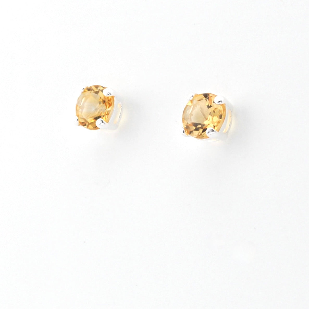 A pair of round-cut yellow gemstone stud earrings set in sterling silver on a plain white background.