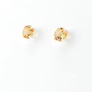 A pair of round-cut yellow gemstone stud earrings set in sterling silver on a plain white background.