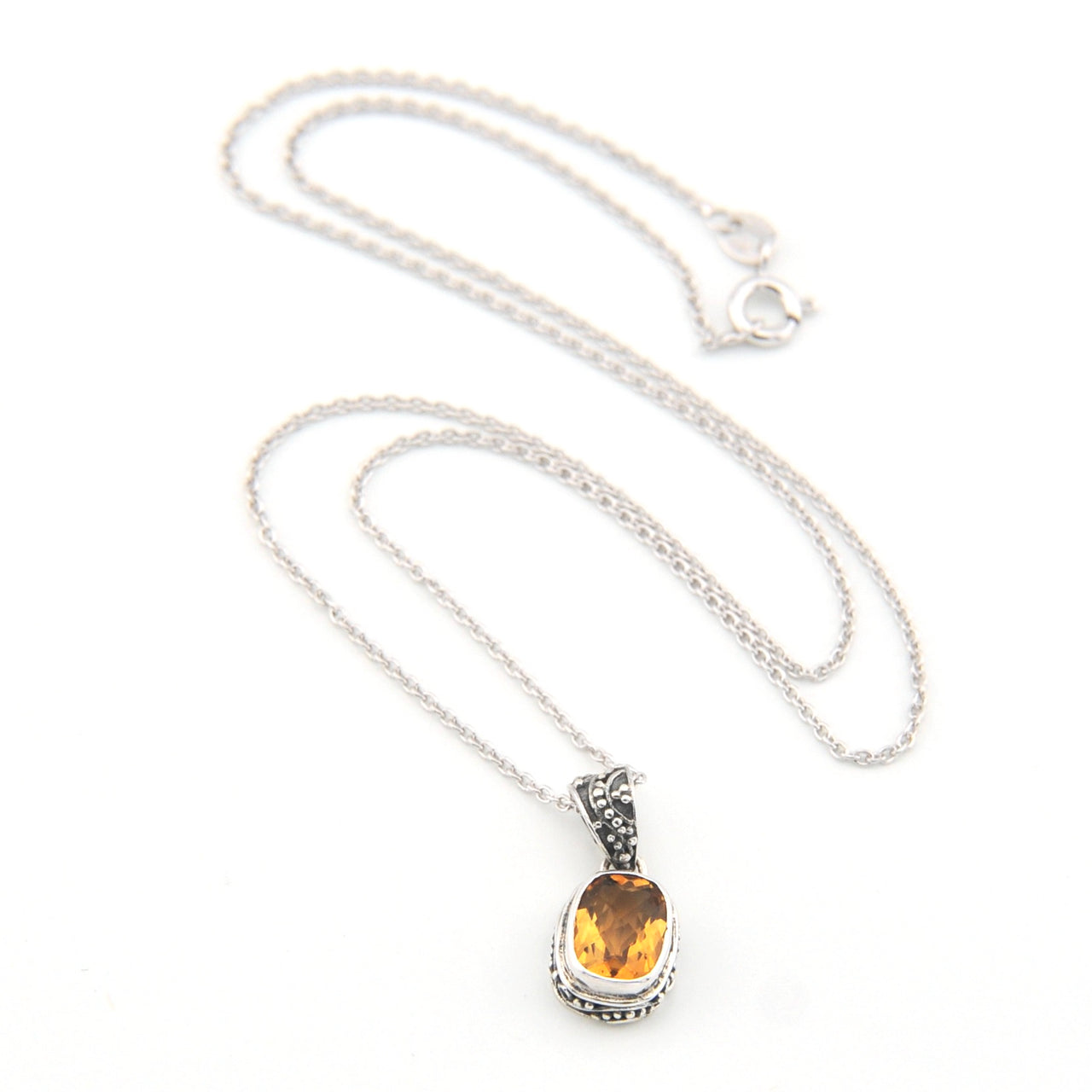 Silver necklace with a pendant featuring a yellow gemstone on a white background