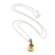 Silver necklace with a pendant featuring a yellow gemstone on a white background