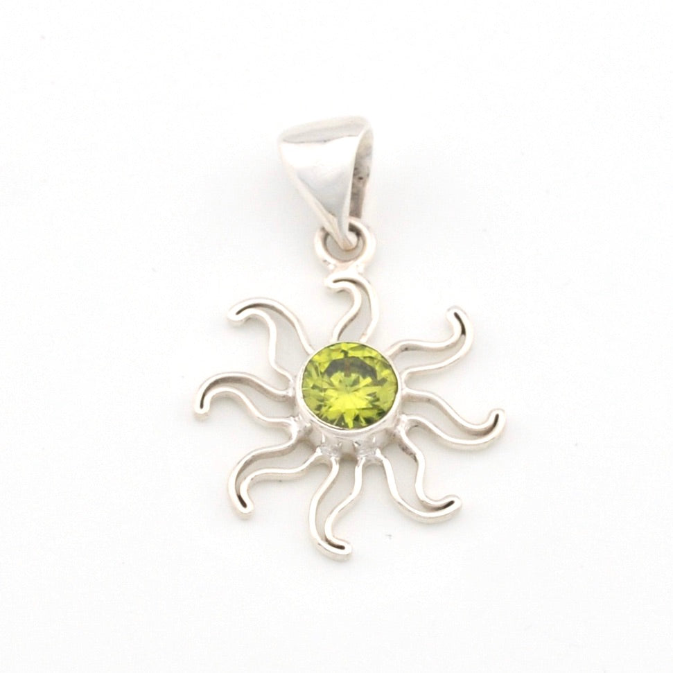 Silver sun-shaped pendant with a green gemstone on a white background