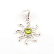 Silver sun-shaped pendant with a green gemstone on a white background