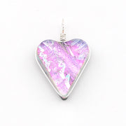 A heart-shaped glass pendant with a vibrant pink, purple, and blue iridescent pattern, set in a silver-toned metal bezel with a silver wire-wrapped loop at the top, shown on a plain white background.
