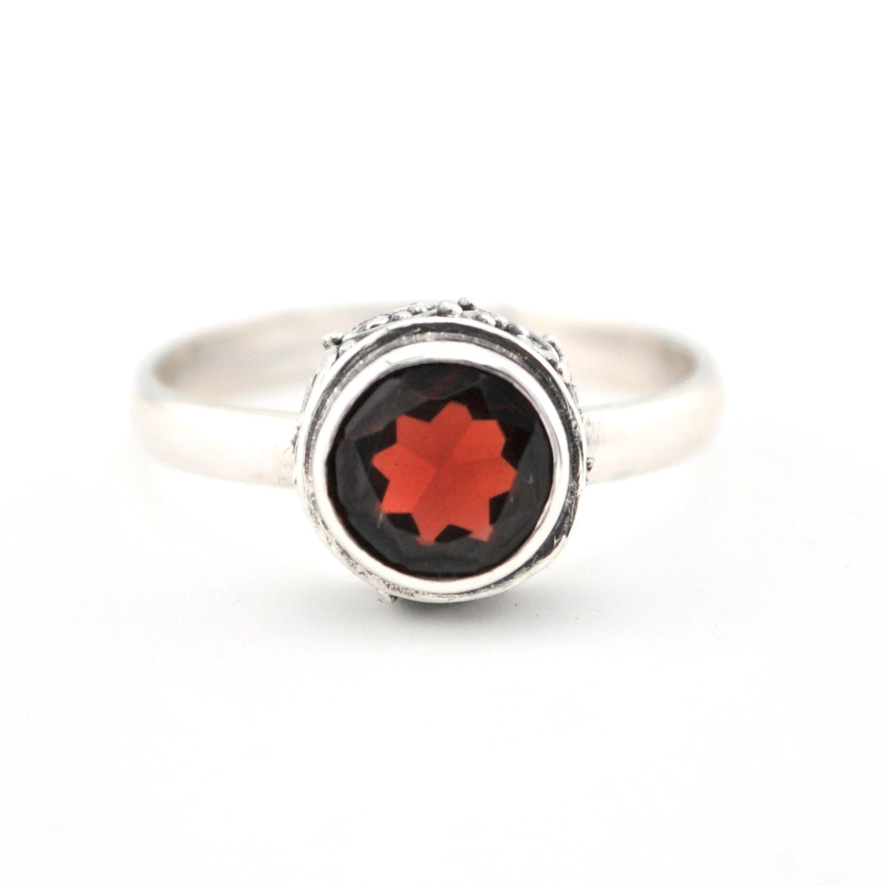 Silver ring with a red gemstone on a white background