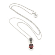 A silver chain necklace with a silver pendant featuring a round, polished dark red gemstone, displayed on a clean white background.