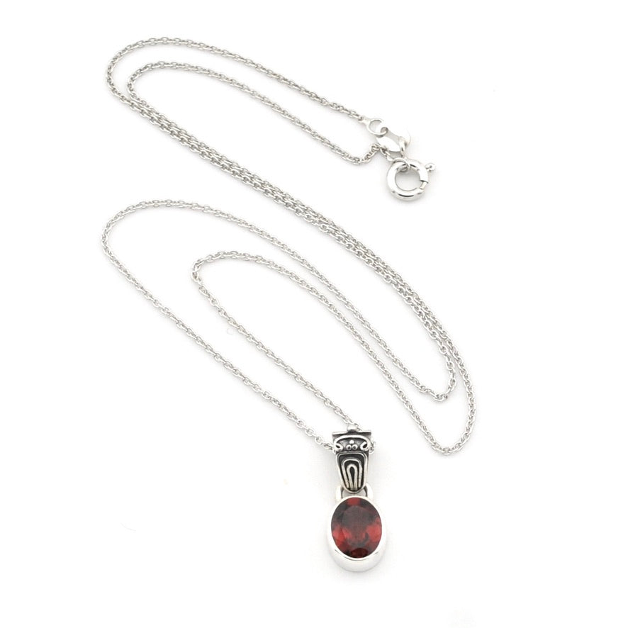 A silver chain necklace with a silver pendant featuring a round, polished dark red gemstone, displayed on a clean white background.