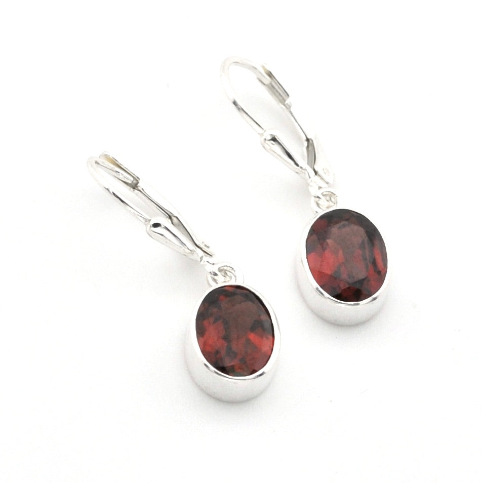 A pair of silver leverback earrings with oval dark red garnet gemstones, shown on a clean white background.