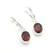 A pair of silver leverback earrings with oval dark red garnet gemstones, shown on a clean white background.