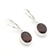 A pair of silver leverback drop earrings with oval dark red garnet gemstones, shown on a clean white background.