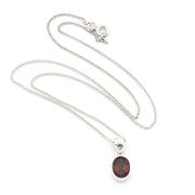A silver chain necklace with an oval dark red gemstone pendant, displayed on a clean white background.