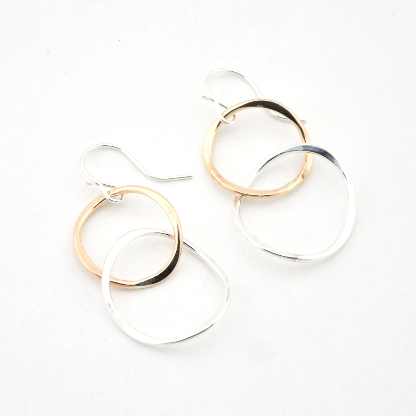 Pair of hoop earrings with gold and silver finishes on a white background